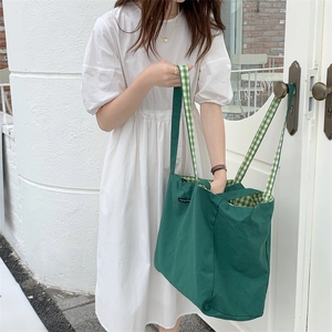 Detail of green canvas tote with green-white checkered straps and merci paris label