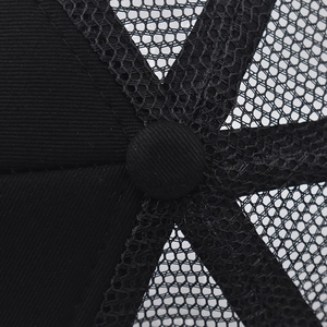 Detail view of the breathable mesh structure and button on top of the black trucker hat