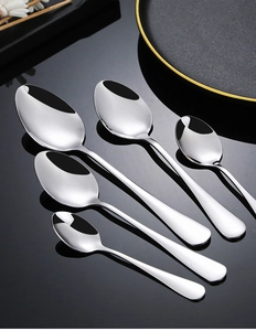 Macro shot of mirror-polished stainless steel spoons in various sizes on a dark plate