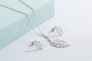 Detailed view of silver hollow leaf pendant necklace and stud earrings set on geometry