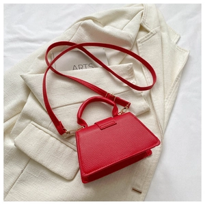 Detail of red textured faux leather handbag with reinforced handle and detachable strap