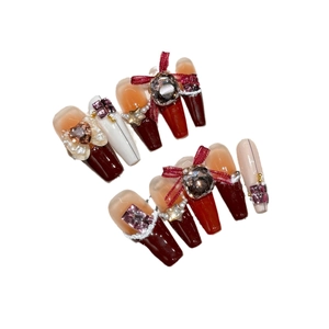 Kit faux ongles faits main avec nœuds rouges, strass en cœur et perles sur blanc