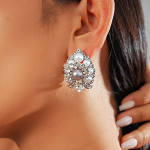 Macro view of crystal flower earrings with grey pearl center and white accents on ear