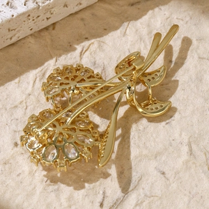 Detail view of the golden metal brooch back with clear cubic zirconia floral accents