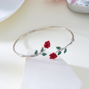 Detailed macro shot of red enamel roses and green leaves on a silver-tone open bangle