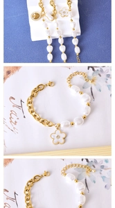 Détail du bracelet en chaîne dorée et perles baroques avec breloques fleur, arbre et cœur