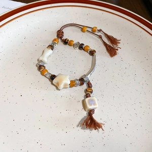 Detail of handmade woven ceramic bead bracelet with star-shaped charms on vintage plate