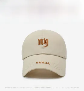 Detail of beige baseball cap featuring brown NY embroidery and breathable laser-cut holes