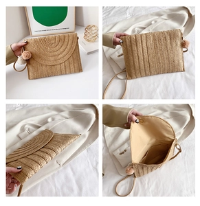 Detail of straw woven envelope bag with colorful pompom charms and magnetic snap closure
