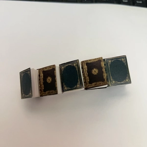 Detailed view of five miniature books with gold patterns on a white background