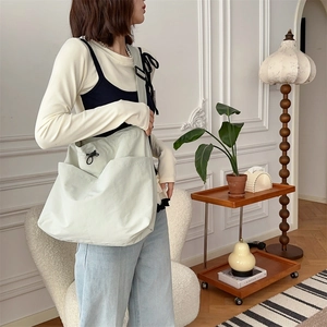 Grande borsa tote in tela verde menta con coulisse mostrata in un contesto lifestyle casual