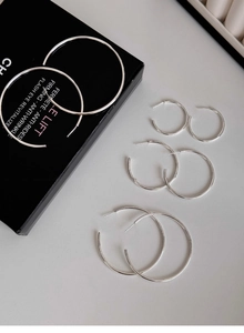 Detailed view of silver hoop earrings in multiple sizes placed on a black gift box