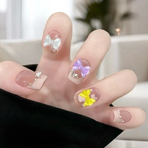 Macro shot of colorful bow ties and pearls nail art accessories on a female hand