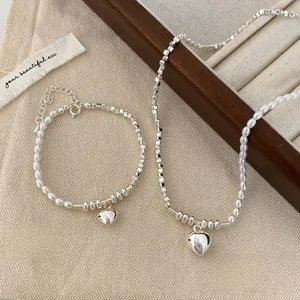 Detailed view of silver heart pendant necklace and bracelet set with pearls