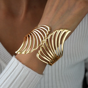 Close-up of golden hollow wing cuff bracelet featuring layered metallic ribbed design