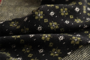 Close-up of soft black knitted fabric with green and white floral patterns