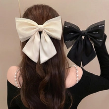 Detailed back view of oversized satin bow hair clips in cream white and black finishes