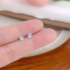 Close-up of mini silver stud earrings with clear zircon held to show small size