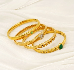 Détail de quatre bracelets en acier titane doré avec pierres colorées sur soie blanche