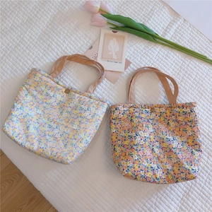 Detailed close-up of floral cotton lunch bags featuring metal snap buttons and handles
