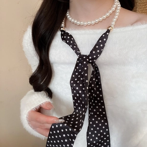 Detail of creative pearl necklace with black and white polka dot chiffon silk scarf