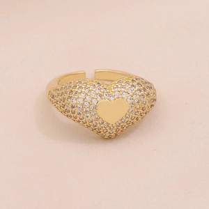 Detail of a gold heart ring featuring pave-set cubic zirconia on a warm textured background