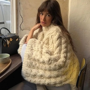 Close-up of thick cable knit texture on cream oversized crewneck sweater for winter