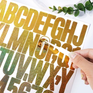 Macro detail of peeling glitter gold letter stickers for DIY gift bags and holiday decor