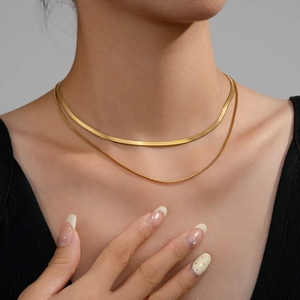 Close-up of layered 18k gold plated jewelry with snake chain and box chain textures