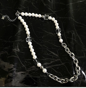 Square crystal and pearl necklace on black marble background with water droplets