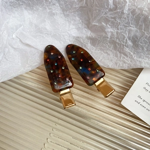 Detail of amber tortoiseshell hair clips with colorful rhinestones on a glass plate