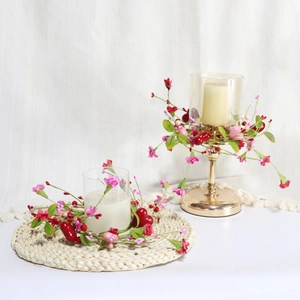 Detail of Valentine candle ring with red pink berries and heart charms on a table