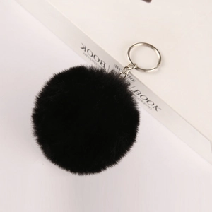 Detail of 8cm black faux rabbit fur pom pom keychain with silver metal clip on books