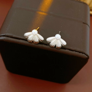 Close-up of matte silver flower earrings with white pearl on a leather box