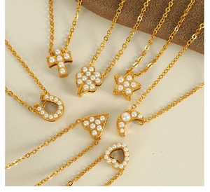 Gros plan de colliers plaqués or avec pendentifs trèfles et croix sertis de perles