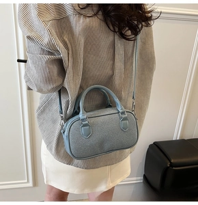 Detail showing the light blue textured mini Boston bag with silver hardware and shoulder strap