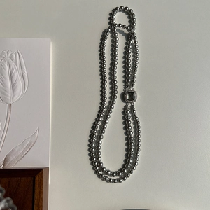 Close-up of double-layer dark gray pearl necklace with a silver zircon square clasp
