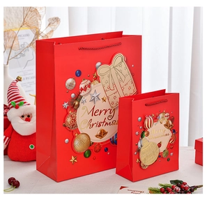 Detail of red Merry Christmas paper gift bags in two sizes with festive holiday decorations