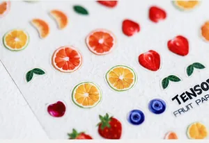 Vue macro de stickers d'ongles 5D gaufrés aux motifs de fraise et d'orange de la série fruit