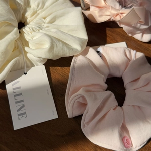 Detail of cream and pink fabric scrunchies with flower button on a wooden background