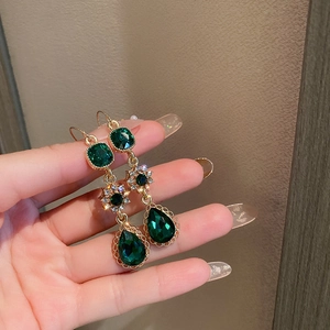 Detailed macro view of vintage emerald green water drop earrings with zircon floral accents