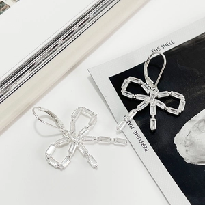 Detailed close-up of 925 sterling silver bow earrings with rectangular zircon stones