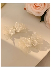 Detail of white mesh butterfly hair clips featuring delicate embroidery and pearls