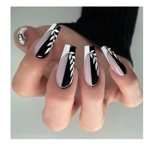 Detail of long coffin press on nails featuring black glossy finish and white leaf patterns