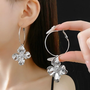 Macro detail of large silver flower drop earrings with metallic texture on model
