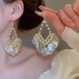 Detail of vintage gold earrings with pearls and cascading white shell tassels