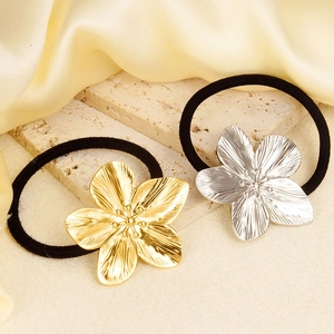 Detail of gold and silver metal flower hair ties on elegant textured silk background