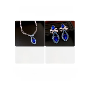 Detail view of blue teardrop crystal necklace and faux pearl earrings on jewelry stands