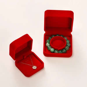 Detail view of red velvet jewelry boxes holding a silver necklace and green bead bracelet