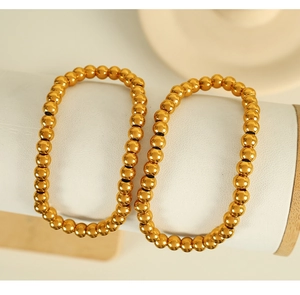 Close-up of golden steel bead bracelets with metallic luster on round stand